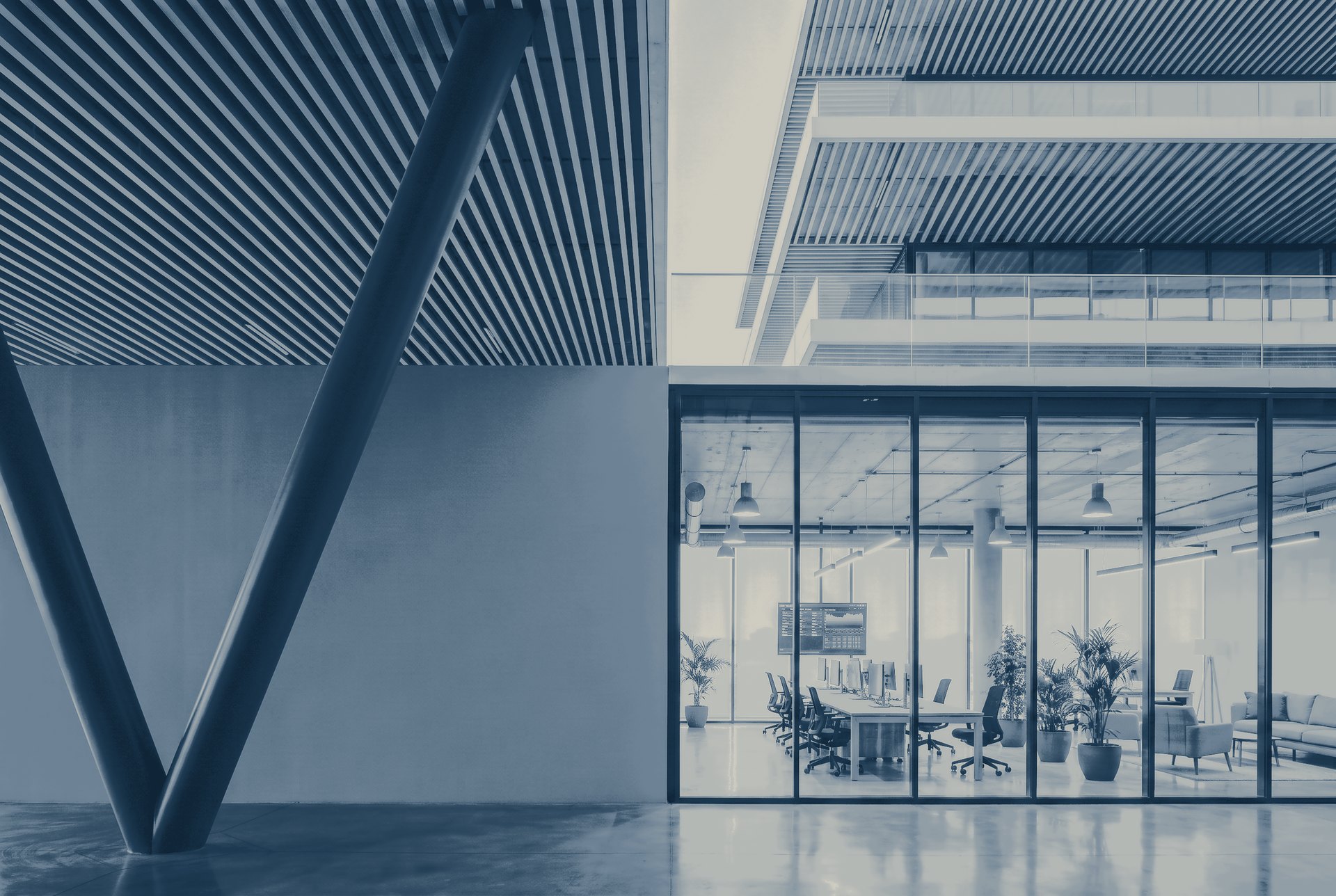 Looking through the glass of a modern building into an open tech office