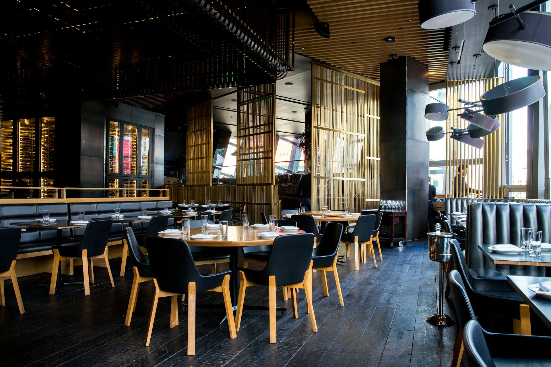 Restaurant dining room with dark wood tables, chairs and warm lighting